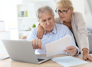 older white couple looking at a laptop and papers