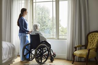 Caregiver with senior woman looking through window