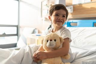 boy sitting in hospital bed with teddy bear