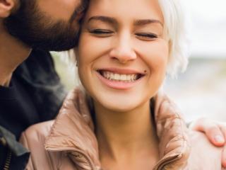 Lady smiling while being kissing on the forehead