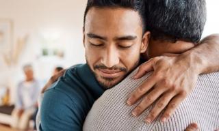 A young man smiles and looks peaceful while hugging his friend