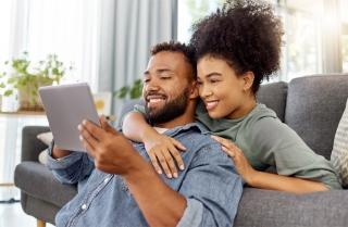 A couple on a couch looking at a tablet