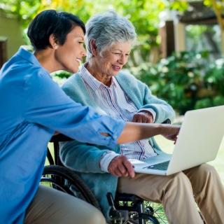 Two women sitting outside viewing a laptop together