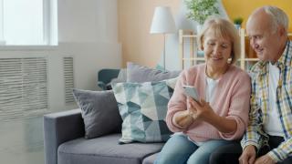 Older couple on a couch looking at phone