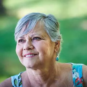 older woman with short gray hair smiling into distance