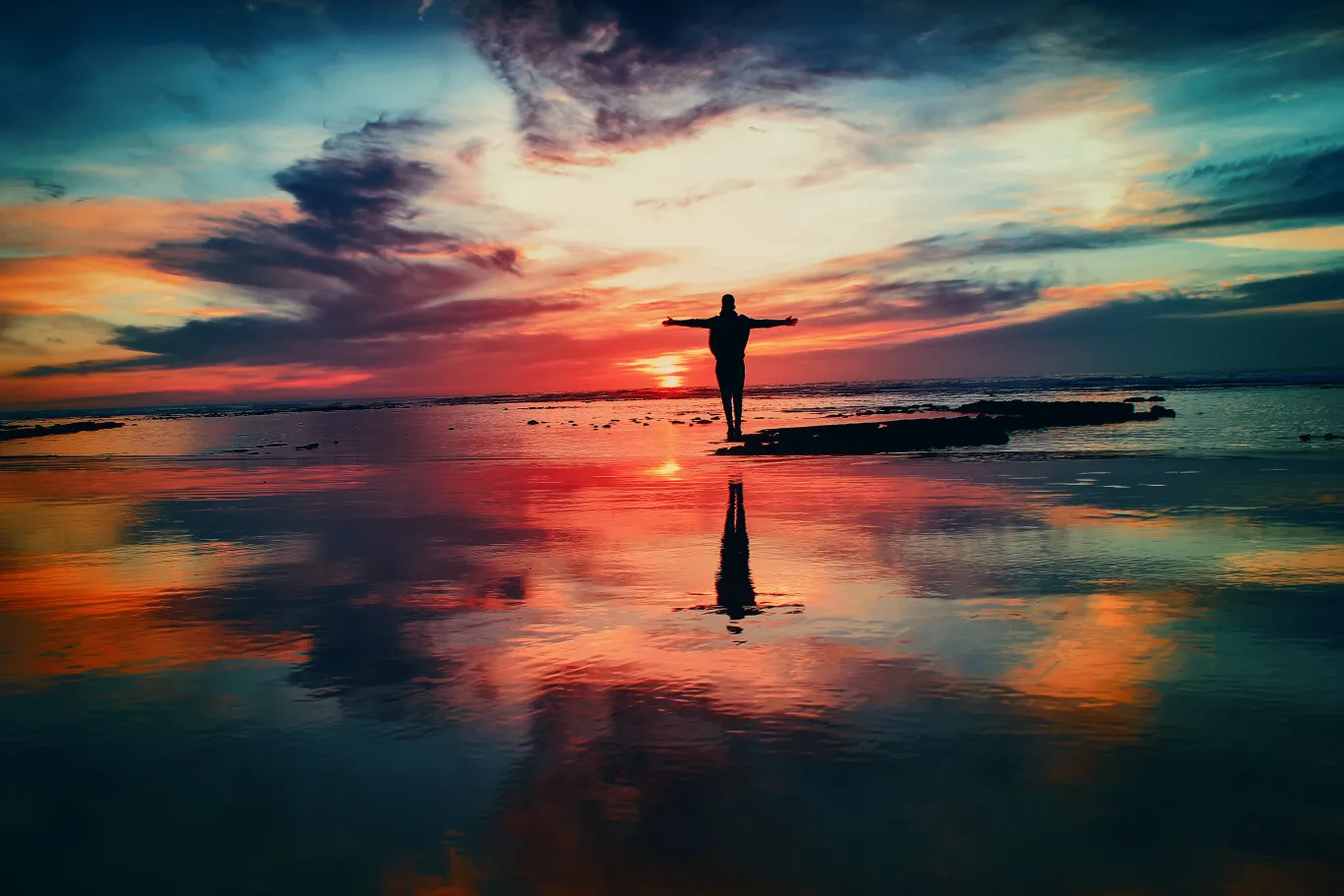 person standing strong on a beach with a sunrise view