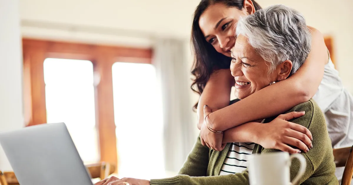 A mother and daughter smiling in front of a laptop