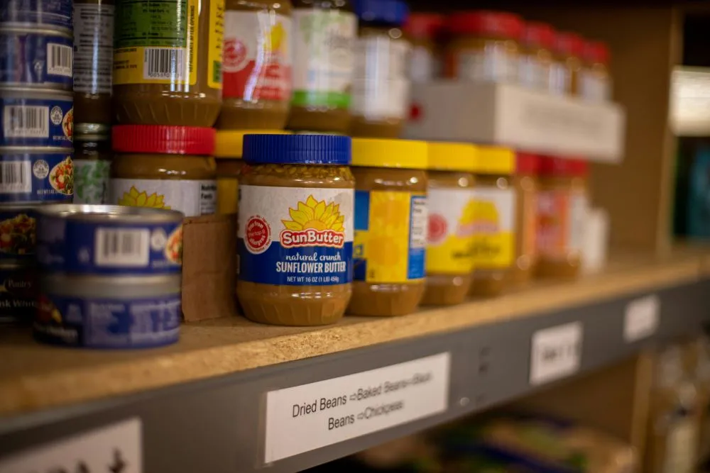 A shelf filled with jars of sunflower butter and cans of tuna