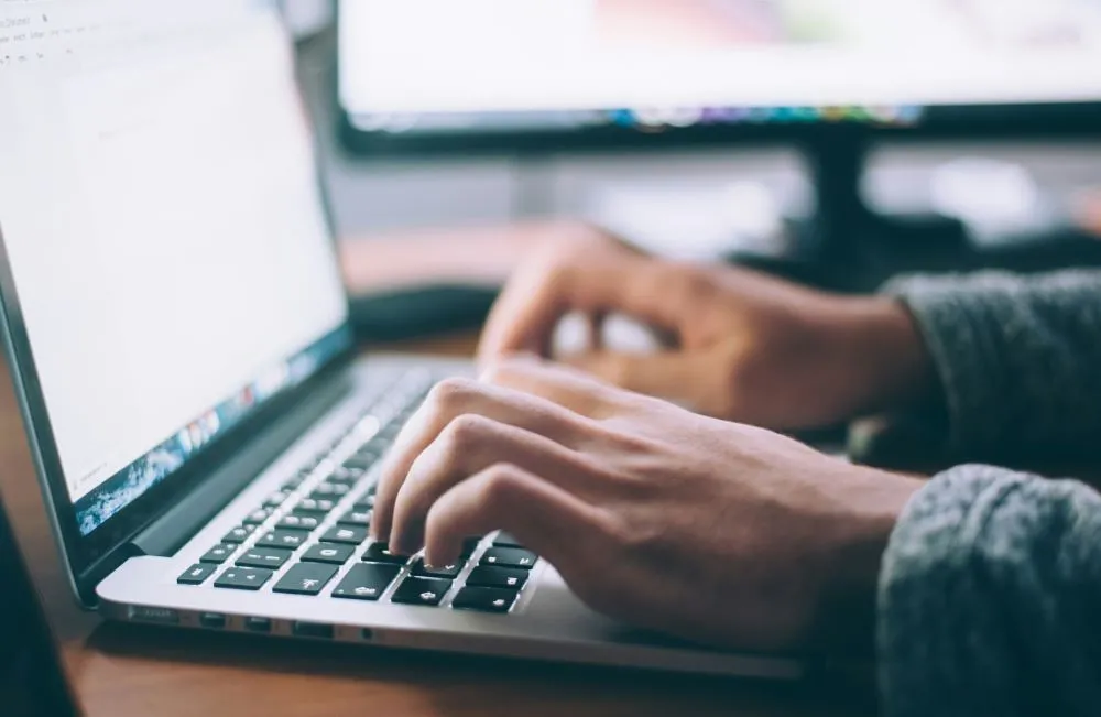 Man's hands typing on laptop keypad