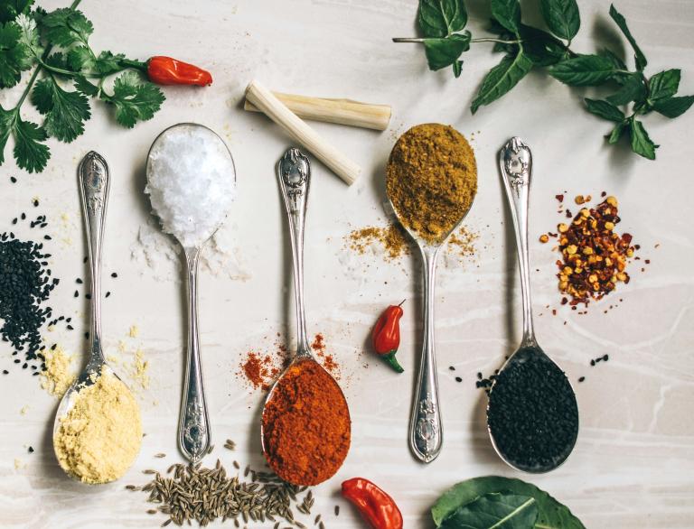 Five spoons filled with colorful spices on a table