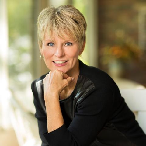 Cancer survivor, author, and survivorship advocate Judy Pearson smiles with her chin resting on her hand