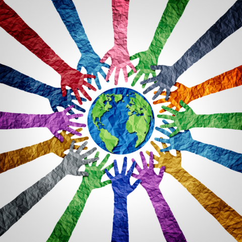 Multi-colored paper cut-outs in the shape of hands are arranged around a blue and green paper cut-out of the Earth