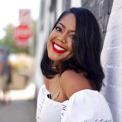 Evelina, a breast cancer survivor, smiles wide on a city sidewalk