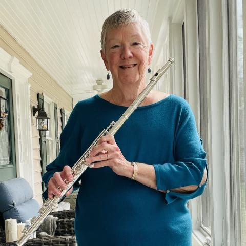 Lyn holds a flute on an enclosed front porch