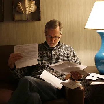 older white man looking over medical bills 