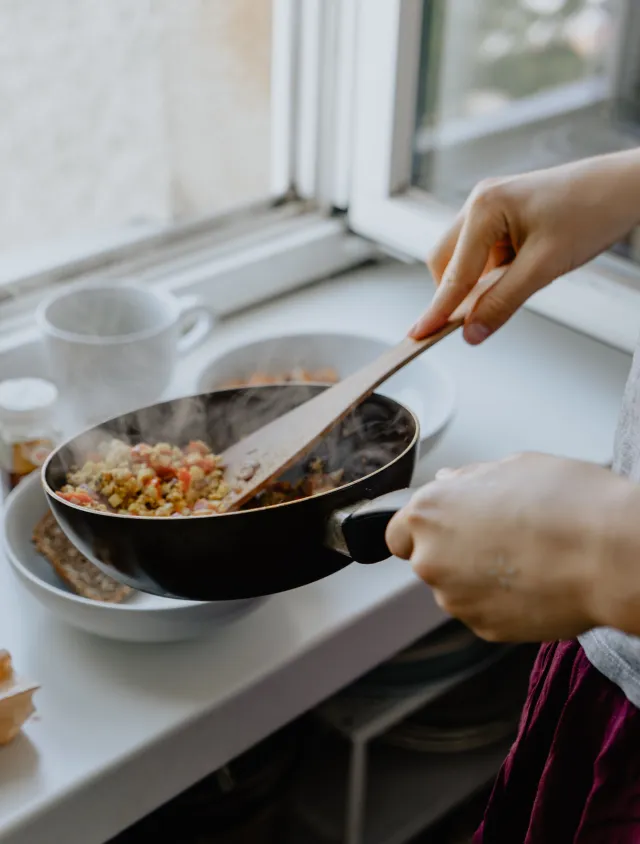 person cooking food in a pan and serving it 