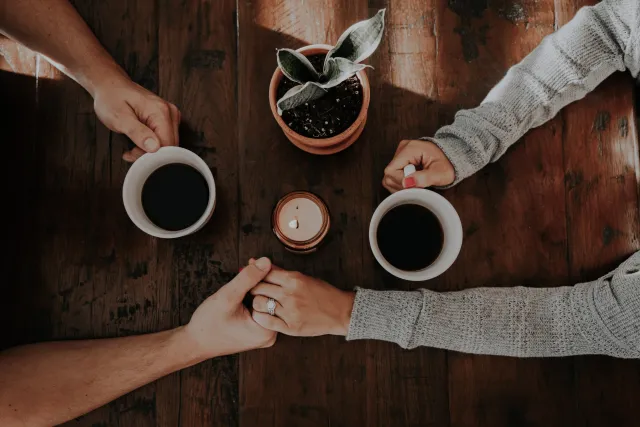 two people holding hands and coffee mugs