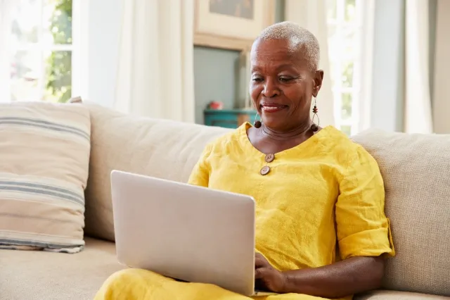 black woman in yellow typing on her computer