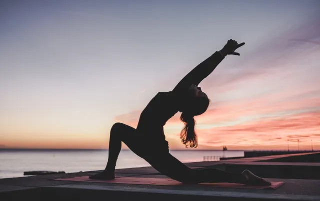 silhouette of a woman doing sunrise yoga