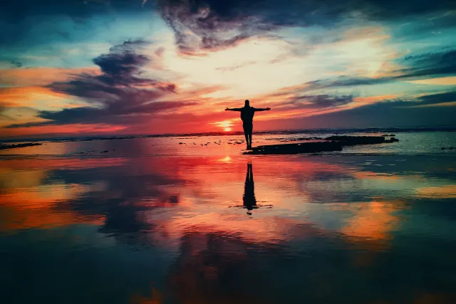person standing strong on a beach with a sunrise view