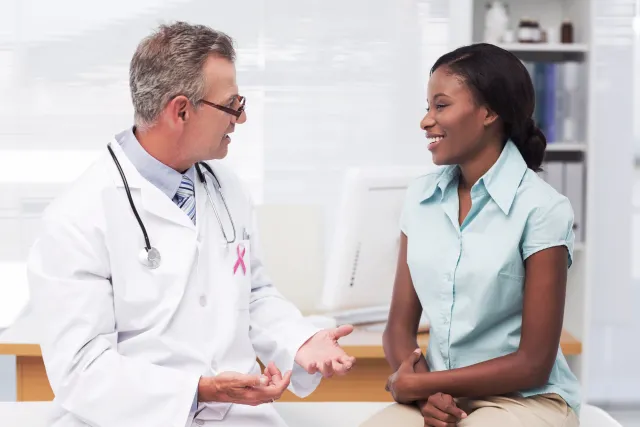 A doctor talks with a patient about her health care decisions in a medical office.