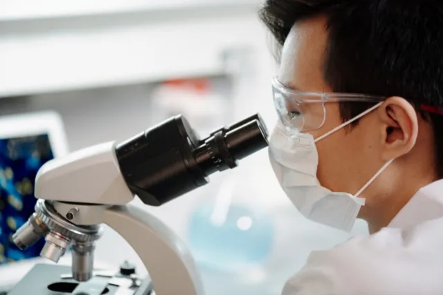 researcher looking through a microscope