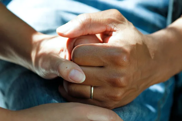 A husband and wife clasp hands to comfort each another