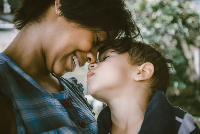 A smiling mother snuggles with her young son