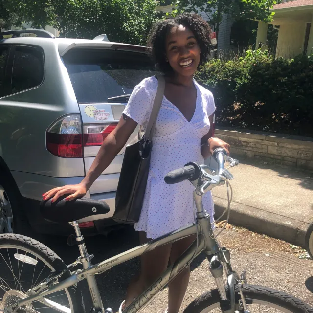CSC's June Advocate Spotlight, Maria Brown, smiles while standing beside her bike outside