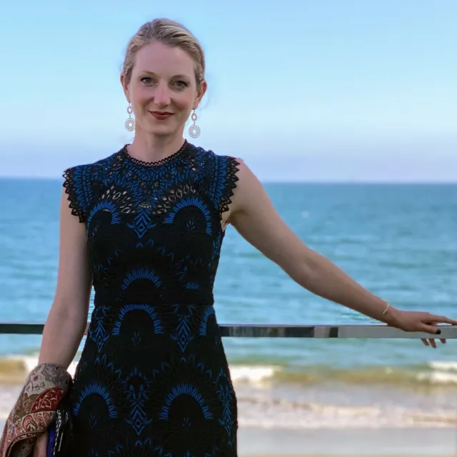 Aaryn Kopp smiles while standing near a lake 