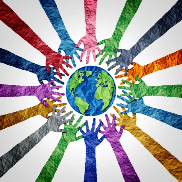 Multi-colored paper cut-outs in the shape of hands are arranged around a blue and green paper cut-out of the Earth