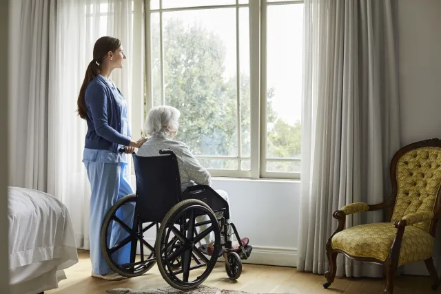 Caregiver with senior woman looking through window