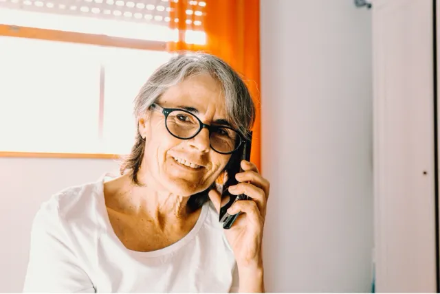 Elderly woman smiles as she talks on the phone