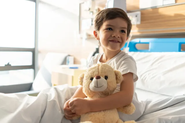 boy sitting in hospital bed with teddy bear