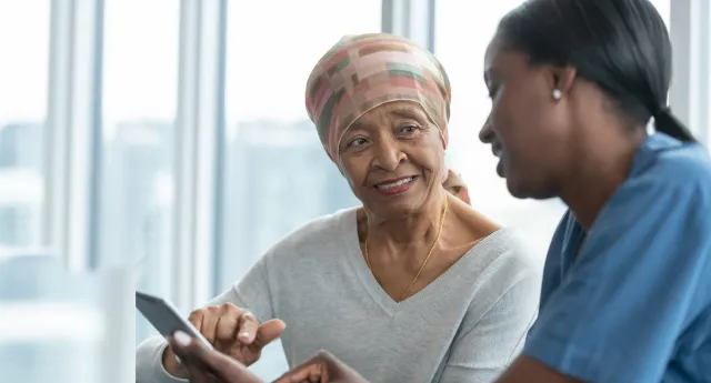 An older African American lady conversing with her nurse