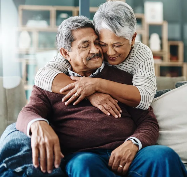 Senior couple at home, with wife hugging partner in support