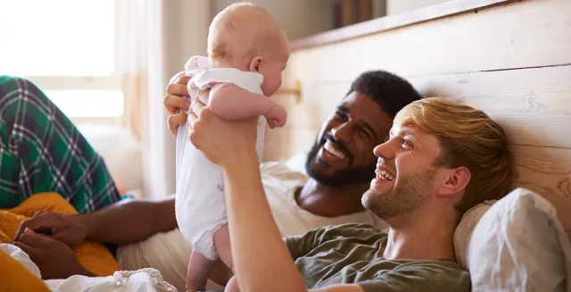 two happy men relaxing with a baby