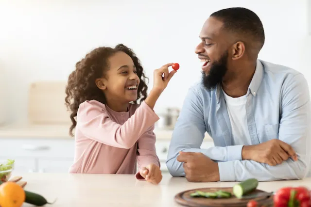 a little girl feeding a berry to her father