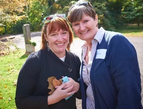 Two people smiling for their photo in the park. 
