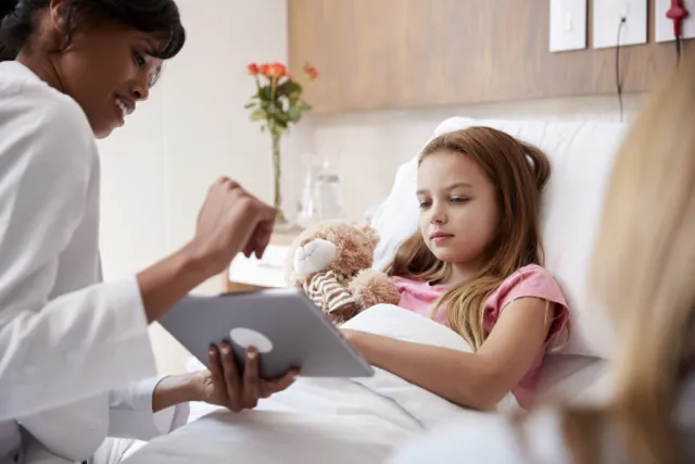 A child in a hospital bed interacting with an tablet