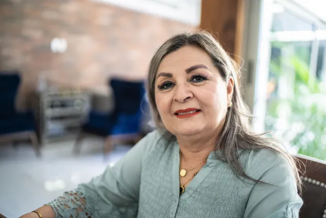 a woman sitting indoors smiling at the camera