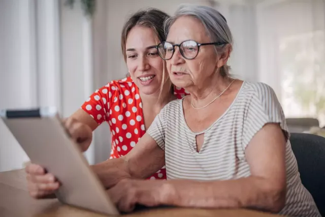 Two seated women review information on a tablet