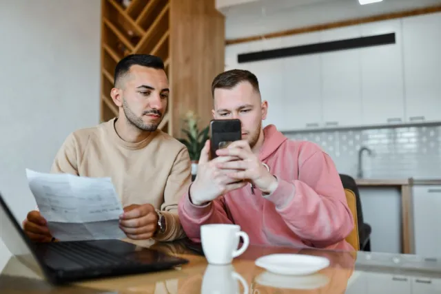 two seated men reading on a phone