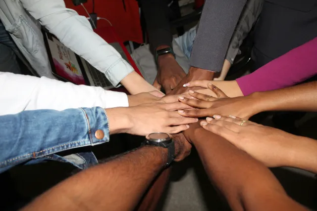 Many people hands meet at the center of their circle