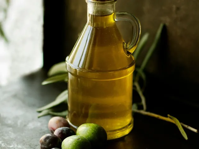 Glass bottle of olive oil on kitchen table in sunlight