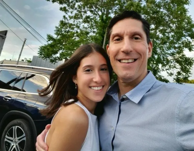 Kayla and her dad smile for an outdoor photograph together
