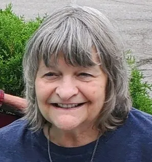 Barbara smiling seated on a park bench