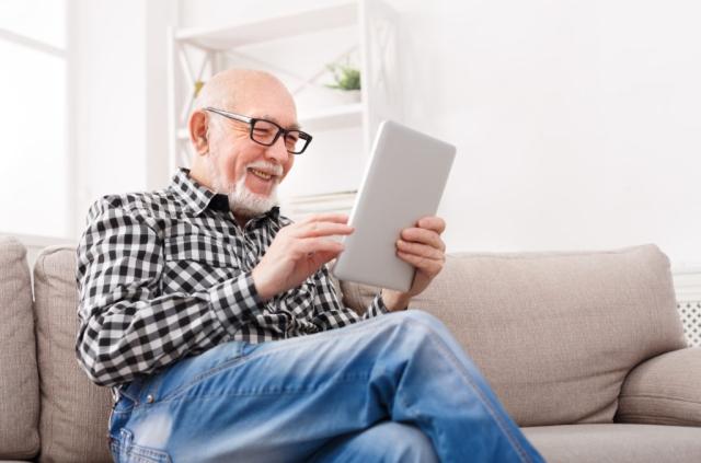 A man smiling while looking at a tablet