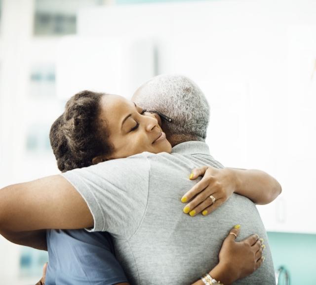 Side view of doctor hugging older adult patient