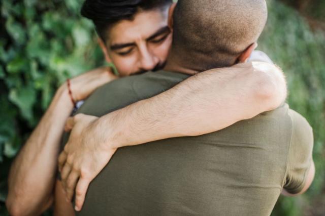 Two men comforting each other with a hug.